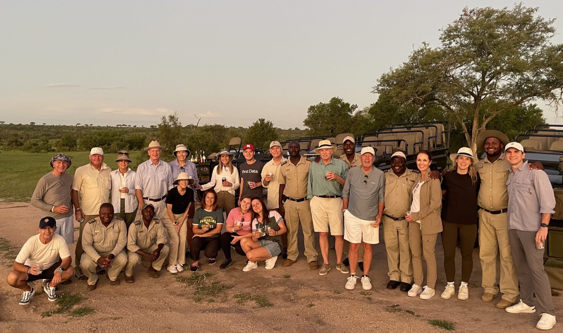 A Kent World Travel group with their guides and safari vehicles at sundown in the bush